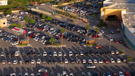 Cars-enter-searching-for-parking-in-crowded-shopping-mall-at-sunset
