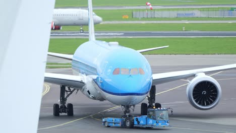 Niederländisches-Flugzeug,-Das-Mit-Hilfe-Eines-Schleppers-Rückwärts-In-Richtung-Landebahn-Fährt