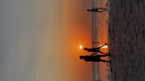 Hochformat:-Silhouette-Männer-Spielen-Beach-Soccer-Mit-Orangefarbenem-Sonnenuntergang
