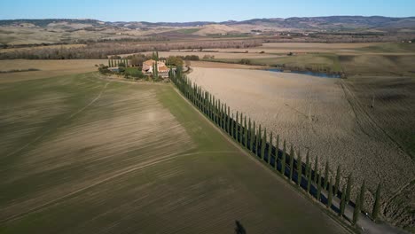 Panoramic-aerial-overview-of-mansion-on-top-of-hill-above-Val-d'Orcia-Tuscany