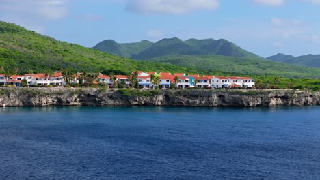Orange-roofed-blue-and-white-sided-buildings-overlook-tropical-Caribbean-sea-cliffs-in-Curacao