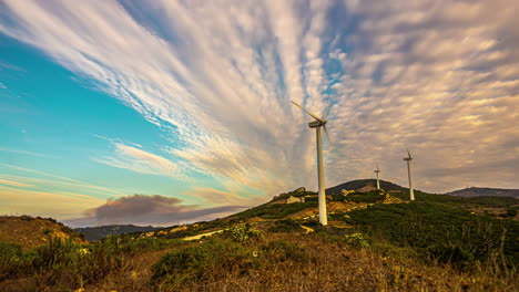 Eine-Zeitrafferaufnahme-Von-Windkraftanlagen-In-Einer-Bergigen-Landschaft-Und-Einer-Wolkenlandschaft