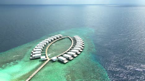 Aerial-view-of-the-honeymoon-suite-huts-on-an-extended-pier-at-Bathalaa-Island,-Maldives,-Indian-Ocean