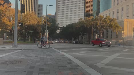 Eine-POV-Aufnahme-Eines-Fahrrads-Beim-Überqueren-Einer-Straße-Und-Eines-Männlichen-Radfahrers,-Der-An-Einer-Ampel-Auf-Bagby-In-Der-Innenstadt-Von-Houston,-Texas,-Wartet