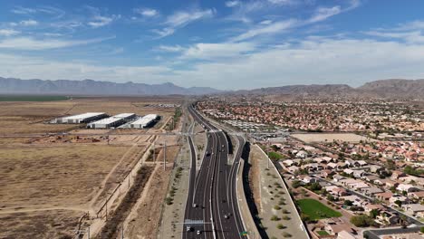 Aerial-View-of-Highway-with-Mountains-in-Background,-Highway-202-in-Phoenix-Arizona,-Estrella-Mountains-and-South-Mountain-with-blue-sky-and-patches-of-clouds