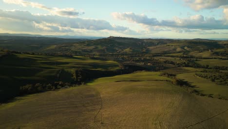 Wide-angle-aerial-view-of-vibrant-orange-green-Tuscan-landscape-establishing-below-stunning-sky