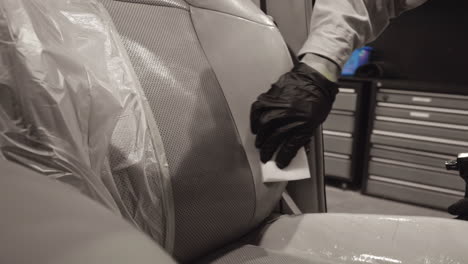 Professional-engineer-wearing-black-gloves-expertly-using-foam-sponge-to-clean-up-car-leather-seat