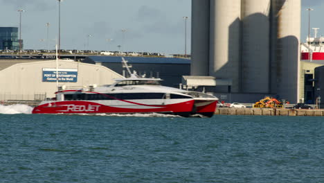 static-shots-of-red-jet-powered-catamaran-ferry-entering-frame-on-the-Solent-in-Southampton-with-weston-in-background