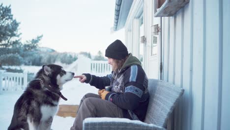 A-Gentleman-Enjoys-a-Warm-Drink-while-Seated-with-His-Alaskan-Malamute-in-Indre-Fosen,-Trondelag-County,-Norway---Static-Shot