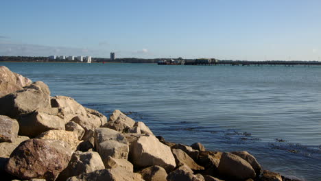Wide-shot-of-rocks-and-stones-on-the-sea-defence-at-Hythe-Marina-village-with-Weston-in-background