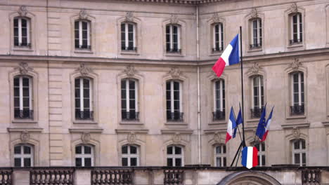 Slow-motion-footage-of-a-small-french-flag-that-is-moving-in-the-wind-in-front-of-a-government-building-in-Paris,-France