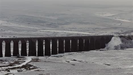 Establishing-Aerial-Drone-Shot-of-Snowy-Yorkshire-Dales-and-Ribblehead-Viaduct-in-Winter-on-Misty-Day-UK