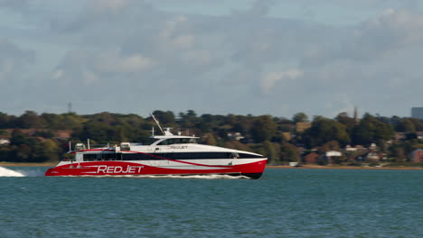 panning-shots-of-red-jet-powered-catamaran-ferry-on-the-Solent-in-Southampton-with-weston-in-background