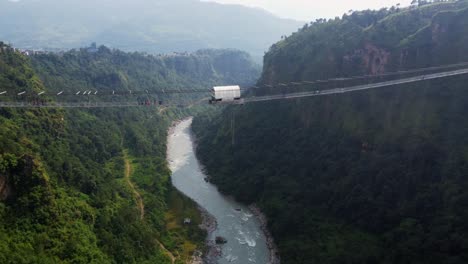 Bungee-Jumping-from-bridge-into-valley-of-Nepal-during-sunny-day,-Aerial-view