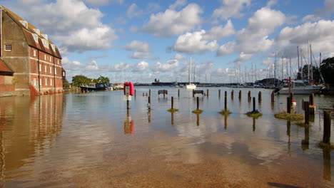 extra-wide-shot-of-water-mill-with-benches-and-pathway-flooded-at-high-tide-at-Ashlett-creek-in-the-Solent,-Southampton