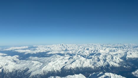Aerial-view-of-The-Alps-Mountains-shot-from-a-jet-cockpit-during-a-real-flight-in-a-splendid-and-bright-winter-morning-with-the-peaks-snowed