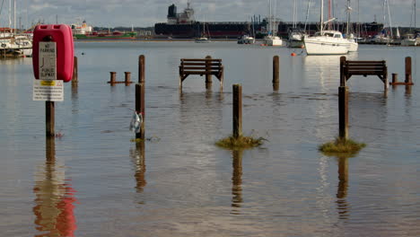 wide-shot-of-benches-and-pathway-flooded-at-high-tide-at-Ashlett-creek-in-the-Solent,-Southampton