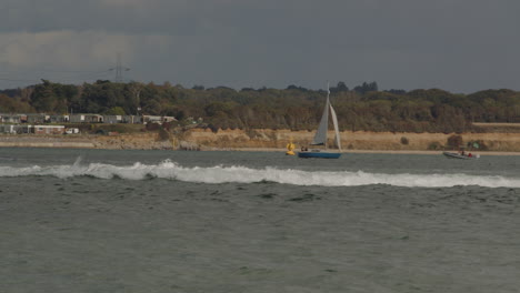 motor-yacht-goes-fast-through-the-frame-at-Calshot-spit,-Solent-Southampton-with-Weston-in-background
