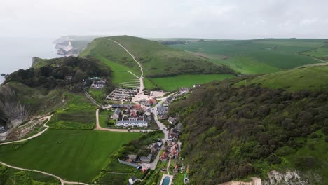 Flight-over-Lulworth-Village-on-Dorsets-Jurrassic-Coast-with-views-over-distant-cliffs-and-rolling-green-countryside