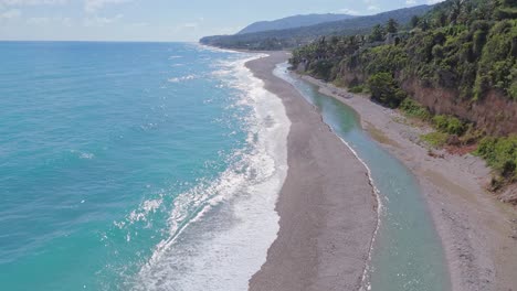 Aerial-Forward-flight-along-beach-and-shoreline-of-Los-Patos-in-Barahona-during-sunny-day,-Dominican-Republic