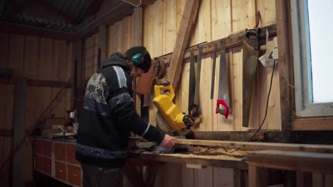 A-Man-is-Sawing-Through-a-Piece-of-Lumber-in-Indre-Fosen,-Trondelag-County,-Norway---Static-Shot