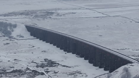 Pullback-Establishing-Aerial-Drone-Shot-of-Snowy-RIbblehead-Viaduct-in-Yorkshire-Dales-on-Gloomy-Day-UK