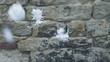 Slowmotion-closeup-of-snowballs-hiting-and-splashing-a-grey-stone-wall