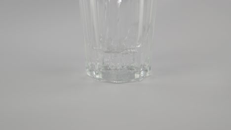 Slowmotion-still-water-pouring-into-clear-glass-in-front-of-neutral-background