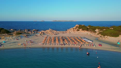 Aerial-drone-forward-moving-shot-over-tourists-sunbathing-in-Punta-Molentis-Beach,-Villasimius,-South-Sardinia,-Italy-during-evening-time