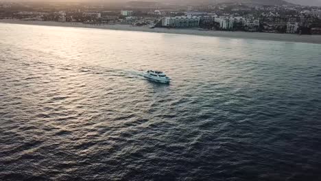Drone-shot-at-sunrise-following-a-yacht-in-the-Sea-of-Cortez,-Los-Cabos,-Mexico