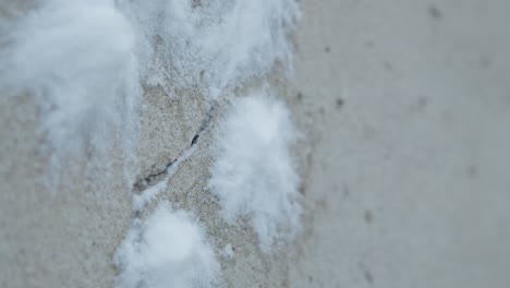 Slowmotion-closeup-of-snowballs-hiting-and-splashing-a-concrete-grey-wall-with-crack
