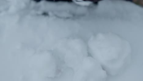 Slowmotion-closeup-of-grabing-and-removing-pile-of-snowballs-with-black-gloves