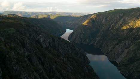 Panoramic-aerial-overview-of-Rio-Sil-river-and-Canyon-as-golden-hour-light-spreads-on-rolling-green-hills-of-valley