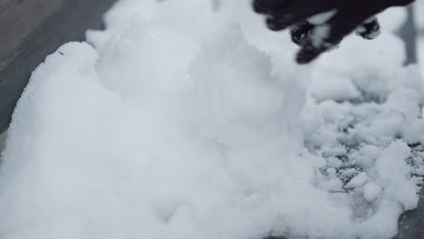 Slowmotion-closeup-of-preparing-pile-of-snowballs-with-black-gloves
