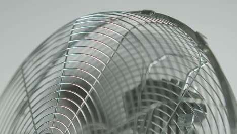 Slowmotion-black-fan-blades-of-a-metalic-ventilator-in-front-of-white-background