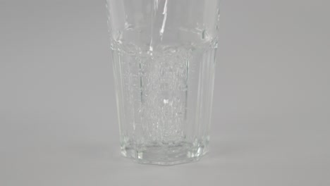 Slowmotion-still-water-pouring-into-clear-glass-in-front-of-neutral-background