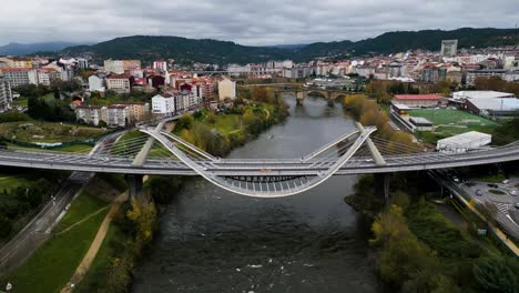 Césped-Verde-Y-Puente-Romano-Detrás-Del-Puente-Del-Milenio-Río-Miño-En-Ourense,-Galicia,-España