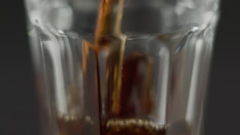 Coca-Cola-En-Cámara-Lenta-Vertiendo-En-Vidrio-Transparente-Frente-A-Un-Fondo-Oscuro