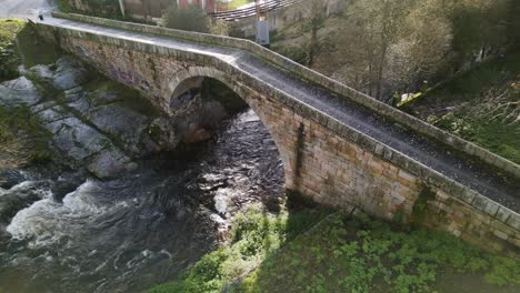 Drone-descends-on-triangular-bridge-under-early-morning-light-in-lonia-river-Ourense-Spain