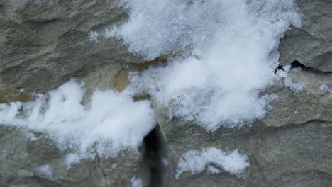 Slowmotion-closeup-of-snowball-hiting-and-splashing-a-grey-stone-wall