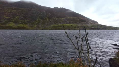 Hillwalking-in-Ireland-wind-sweeps-plume-of-water-across-Coumshingaun-Lake-Comeragh-Mountains-Waterford-on-a-winter-morning