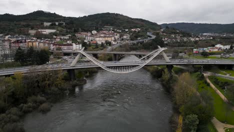 Slow-parallax-around-Millennium-Bridge-Miño-River-in-Ourense,-Galicia,-Spain-as-cars-drive-over-in-fall