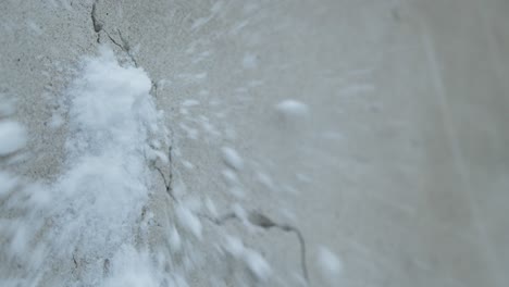 Slowmotion-closeup-of-snowball-hiting-and-splashing-a-concrete-grey-wall-with-crack
