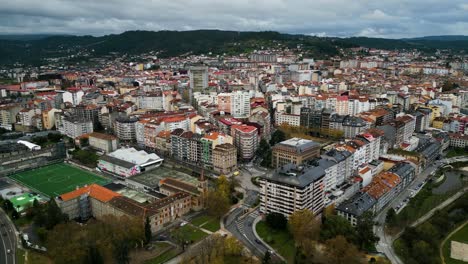 Ourense,-Galicia,-Spain-city-skyline-under-grey-clouds-with-football-field-and-apartment-buildings