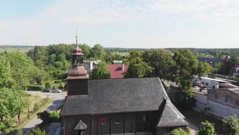 Drone-rises-to-reveal-dark-wooden-church-in-small-rural-village-in-the-countryside