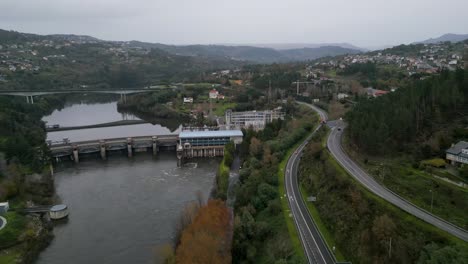 Flyover-above-highway-road-lining-river-by-Velle-water-dam-and-power-plant-in-Ourense,-Galicia,-Spain