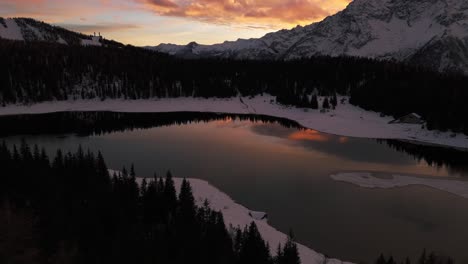 Birdseye-view-of-Palù-or-Palu-lake-in-winter-season-at-sunset,-Valmalenco-of-Valtellina-in-Italy,-aerial-drone-forward