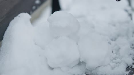 Slowmotion-closeup-of-preparing-pile-of-snowballs-with-black-gloves