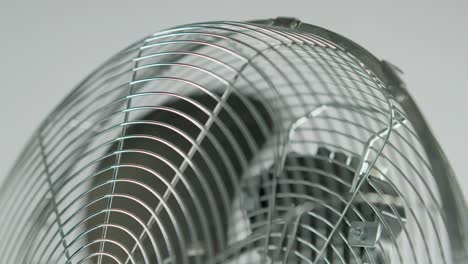 Slowmotion-slowing-down-black-fan-blades-of-a-metalic-ventilator-in-front-of-white-background