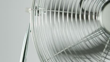 Slowmotion-black-fan-blades-of-a-metalic-ventilator-in-front-of-white-background